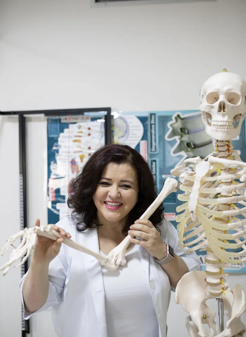 Dr. Neda Nafei smiling beside a spine and skeleton model