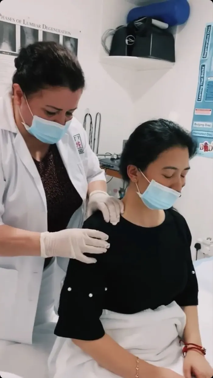 Dr. Neda working on a seated patient's shoulder